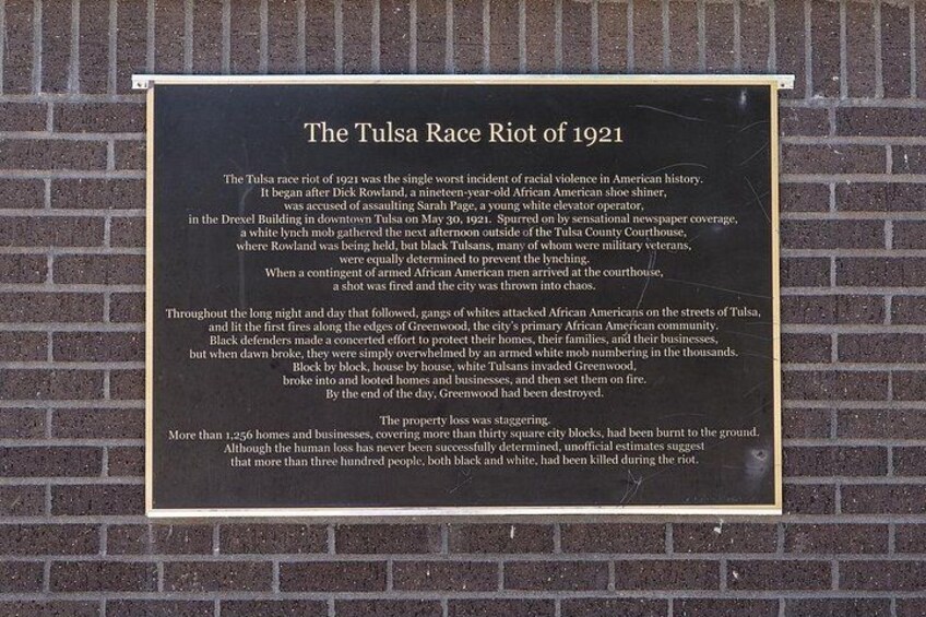 A historical plaque on a brick wall detailing the Tulsa Race Riot of 1921. 4