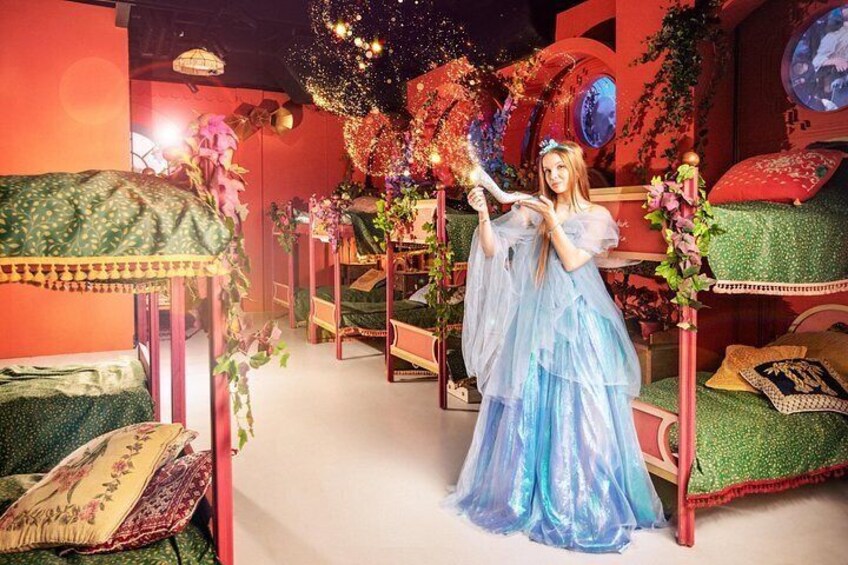 A fantasy-themed room with a bed, a woman in a blue dress, and decorative elements like flowers and a chandelier. 1