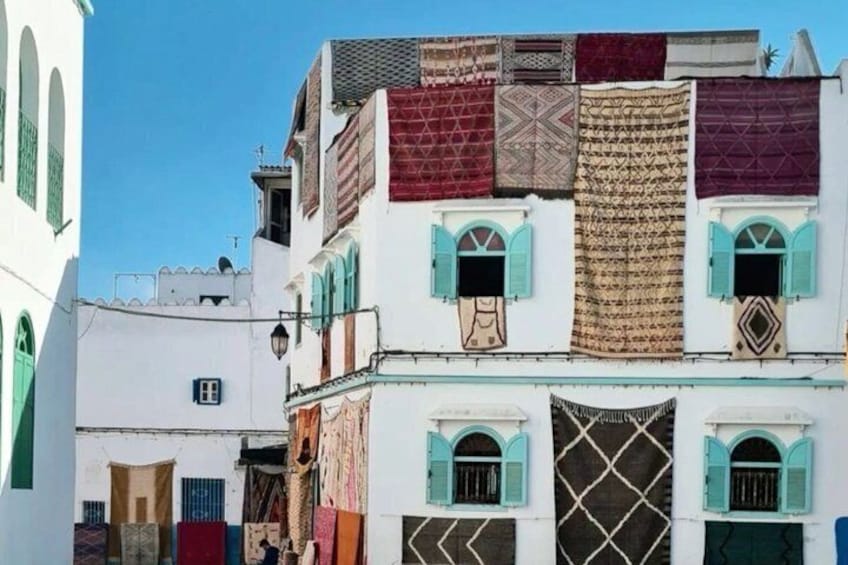 A building with multiple balconies, each adorned with colorful textiles. 5