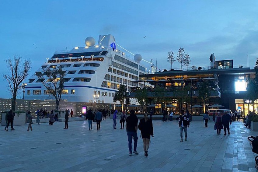A cruise ship docked at a port with people walking around. 4