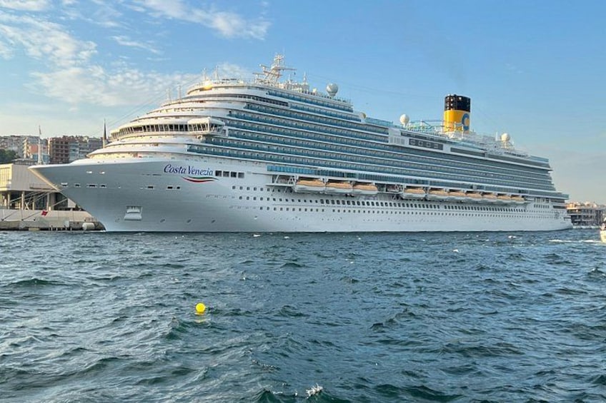 A large cruise ship named Costa Venezia docked at a port with a cityscape in the background. 5
