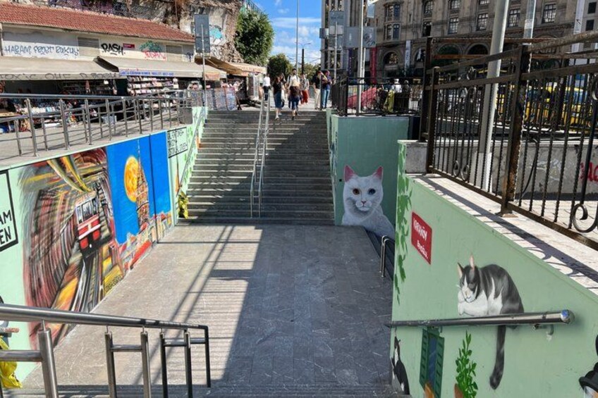 Eine Treppe mit Wandgemälde, Katzenillustration und Metallgeländer. 4