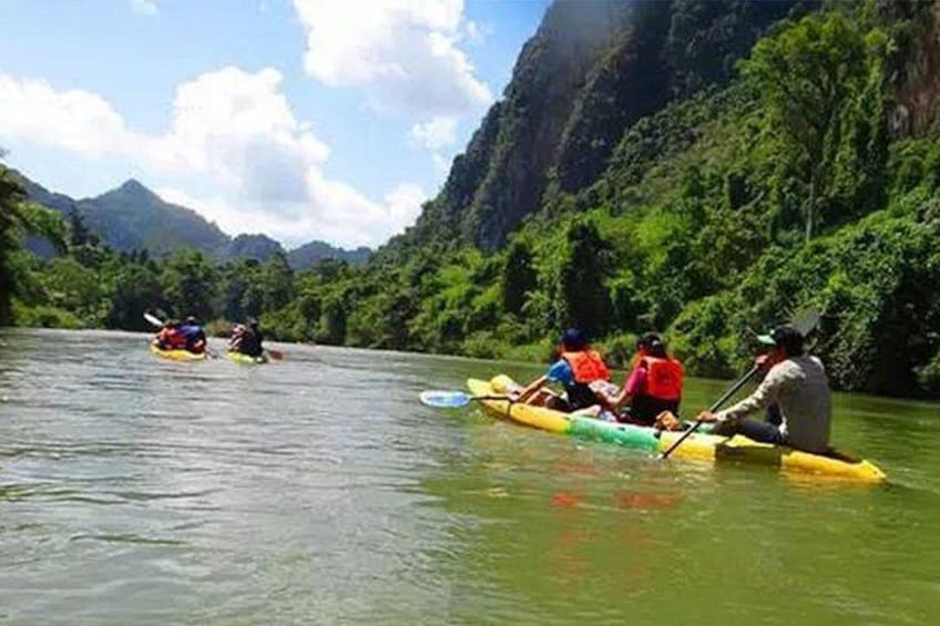 People kayaking on a river surrounded by lush greenery and mountains. 2