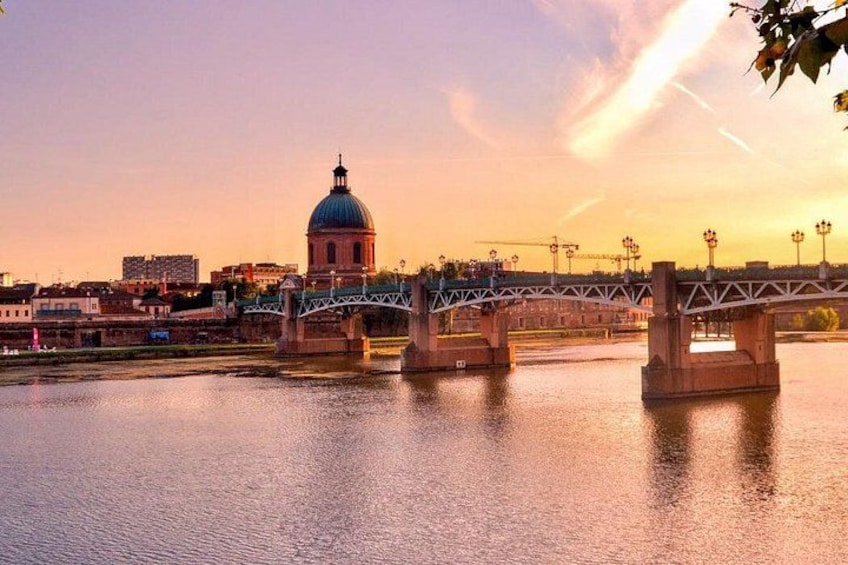 Un pont enjambant une rivière, un bâtiment en forme de dôme et un ciel au coucher du soleil. 1