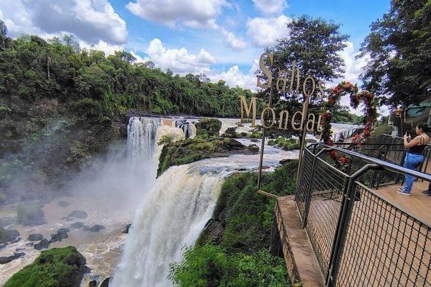 Una cascada, un letrero de madera y una barandilla. 5
