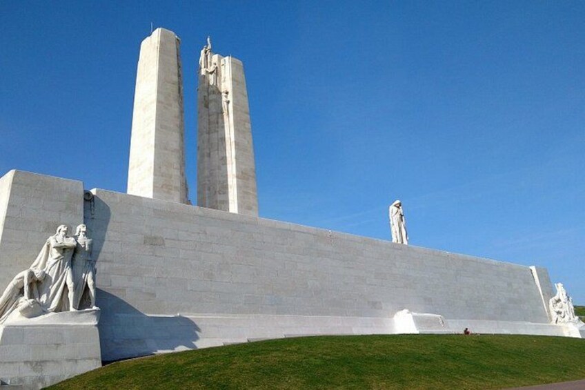 A large monument with two tall columns and statues on a grassy hill. 5