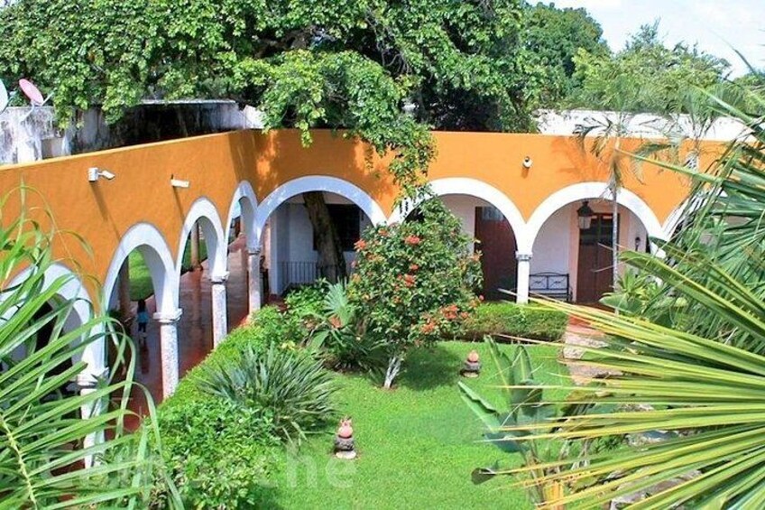 A courtyard with arches, a tree, and a small statue. 5