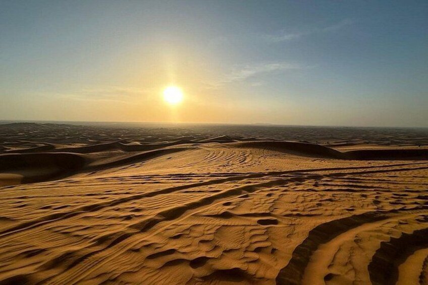Un paysage désertique avec des dunes de sable et un soleil couchant. 3