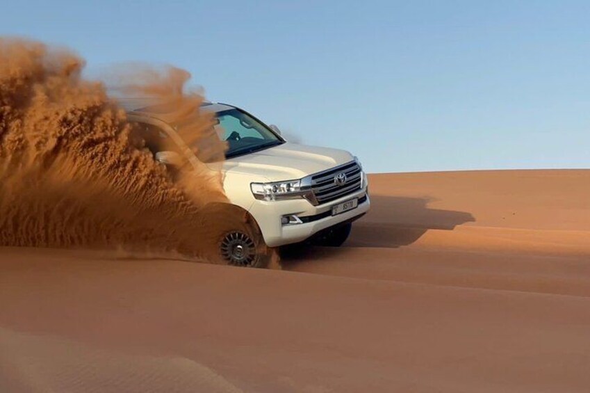 Un VUS blanc roule dans le désert, et ses pneus soulèvent des nuages de sable. 4