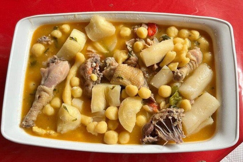 Een witte, rechthoekige schaal met stoofpotje, kip, aardappelen en kikkererwten. 1