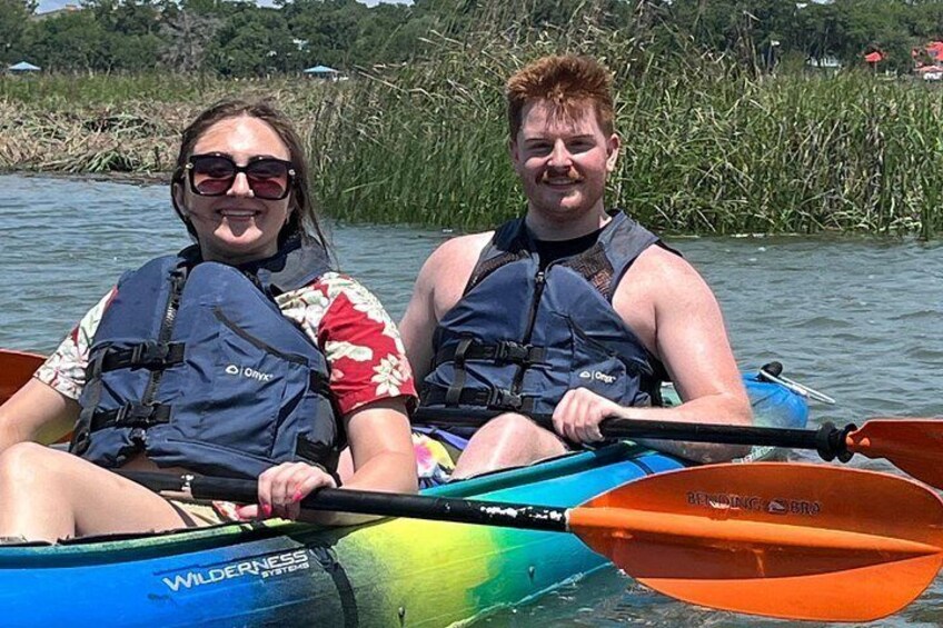 Twee personen in een kajak op een rivier, omringd door begroeiing. 4