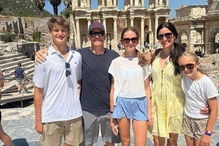 A group of people standing in front of ancient ruins with columns and steps. 1