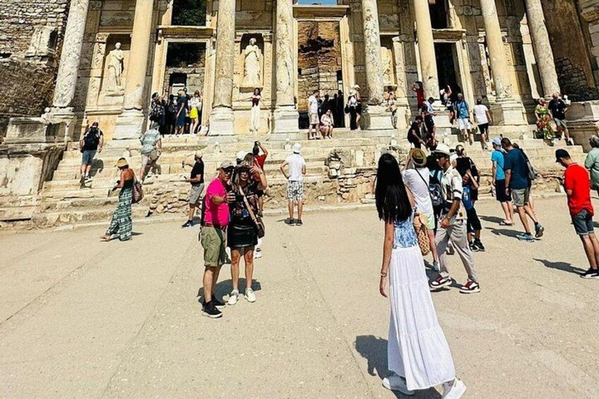 A historical building with columns and steps, surrounded by tourists. 3