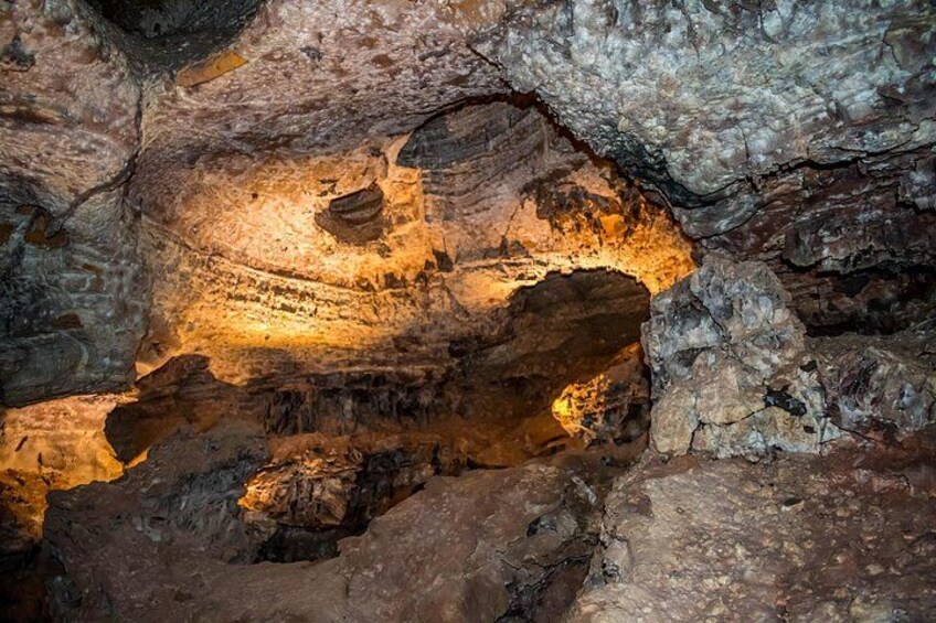 A cave interior with rock formations and illuminated areas. 2