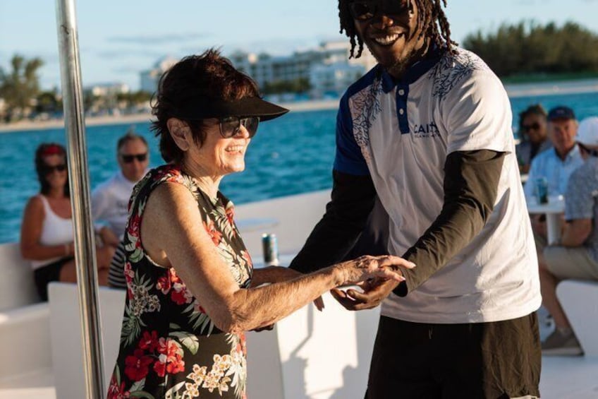 Two people on a boat, one wearing a floral dress and the other in a white shirt with blue sleeves, holding hands. 3