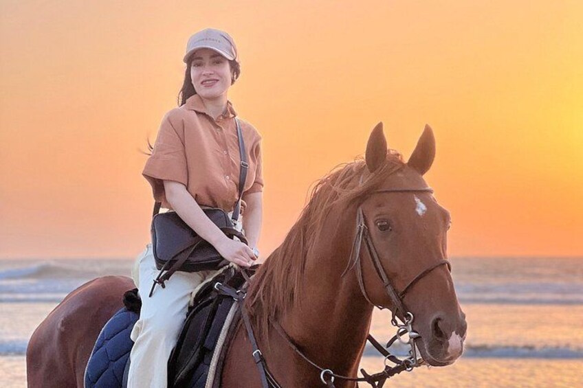 En person rider hest på en strand ved solnedgang. 4