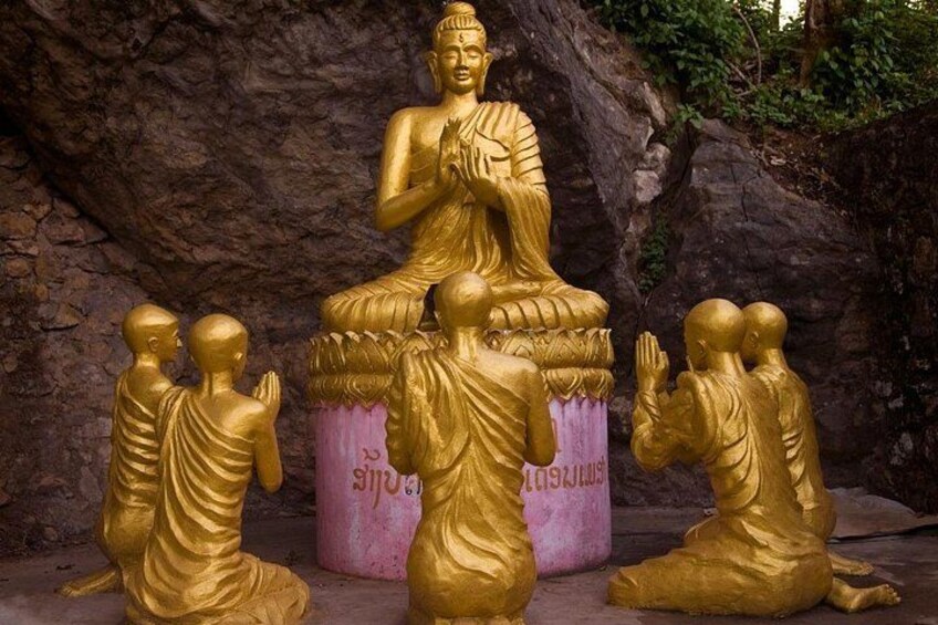A golden Buddha statue with three smaller statues kneeling in front. 5