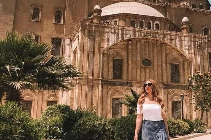 A woman standing in front of a historic building with arches and columns. 4