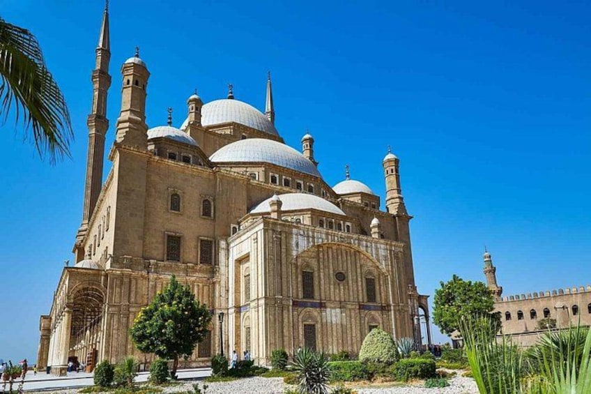 A large mosque with multiple domes and minarets, surrounded by greenery and a clear blue sky. 2