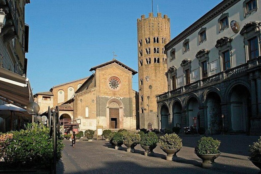 A historic square with a church, a clock tower, and a building with arches. 3