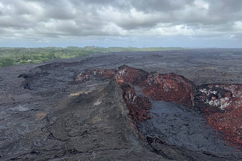 A volcanic landscape with lava flows and a distant green forest. 5