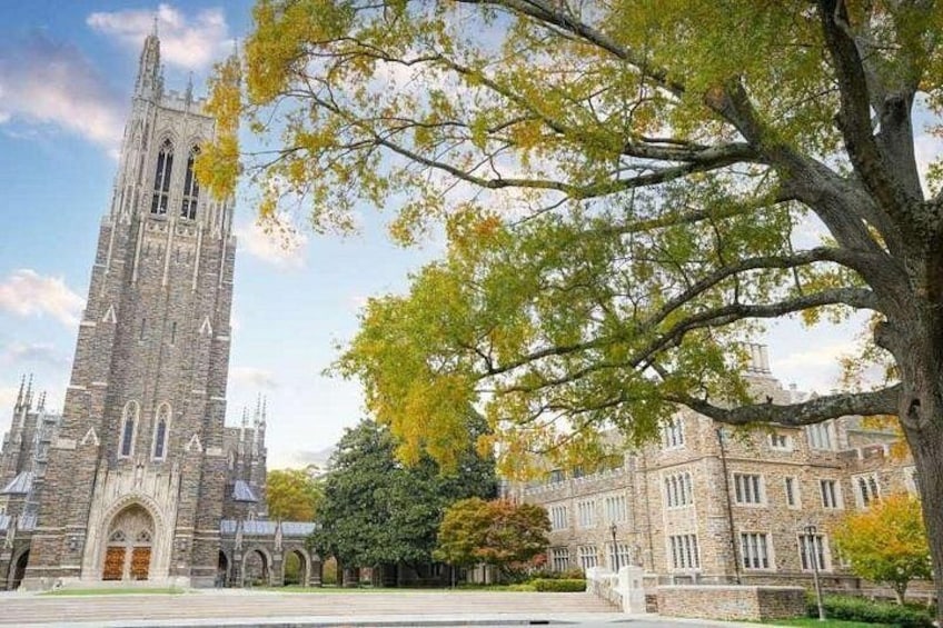 A historic stone building with a tall tower, surrounded by trees with autumn foliage. 2