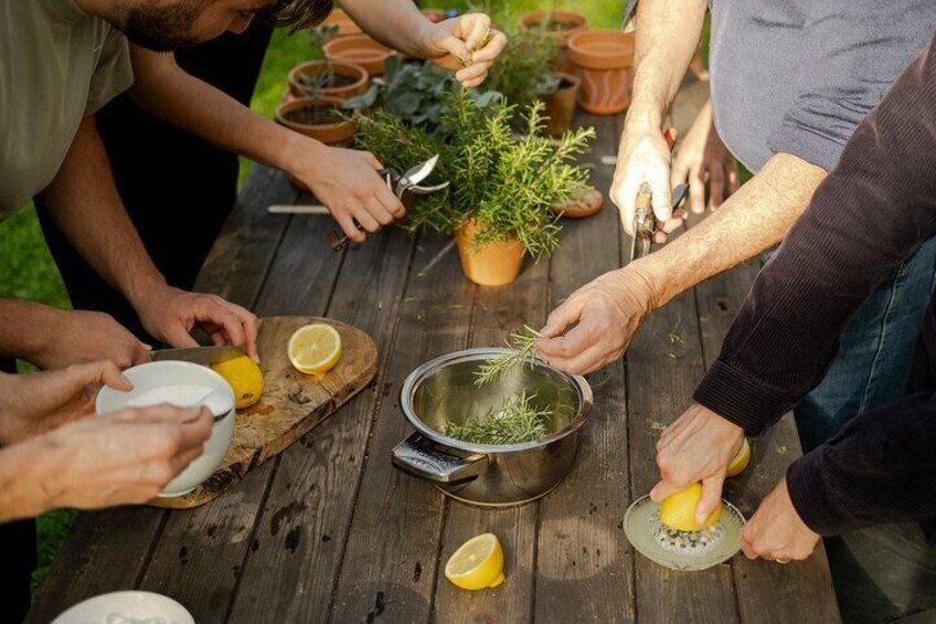 Personas preparando comida al aire libre, usando una mesa de madera, cortando limones y manejando hierbas. 5