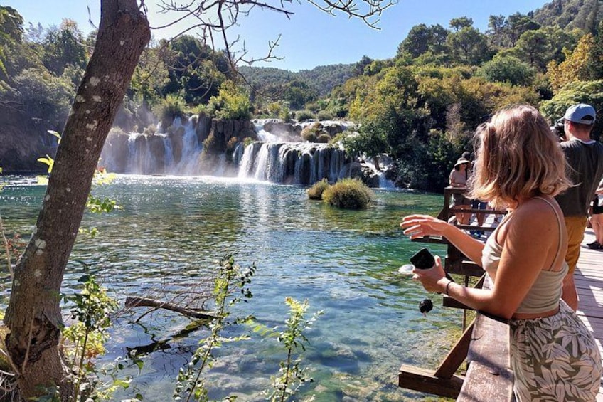 Una mujer fotografiando una cascada con vistas claras al agua y la vegetación circundante. 1