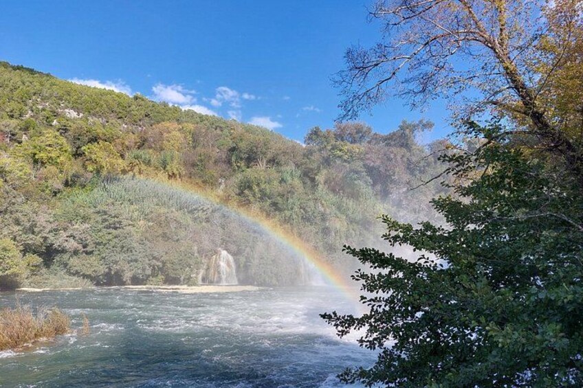 Un río con una cascada, un arcoíris y una ladera boscosa. 3