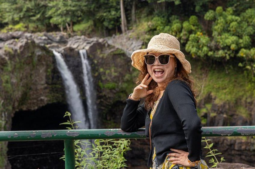 A person standing by a waterfall with greenery in the background. 2
