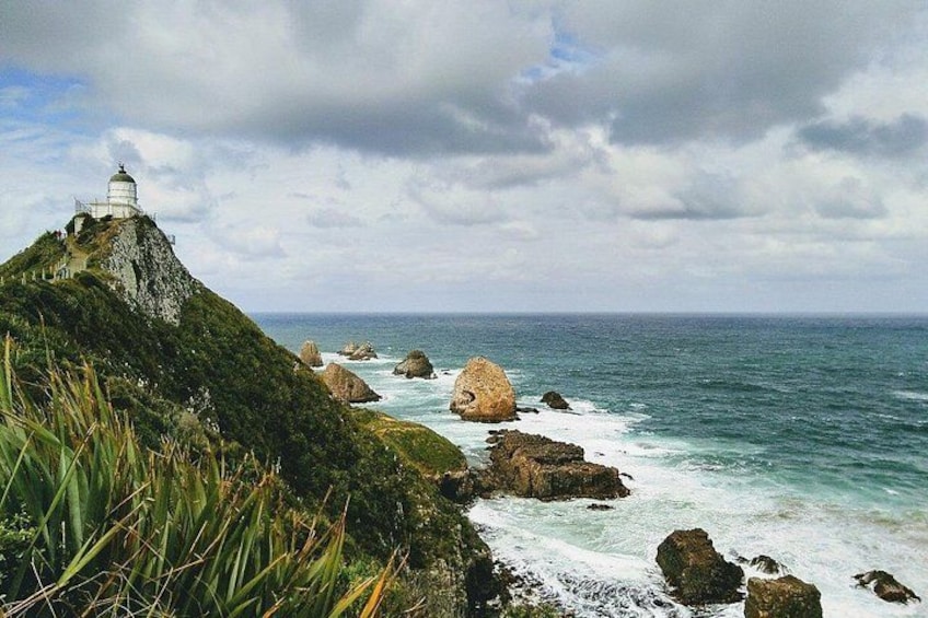 A lighthouse on a cliff, ocean waves, and rocky coastline. 2