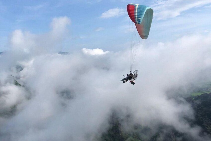 A paraglider flying above clouds with a colorful parachute. 5