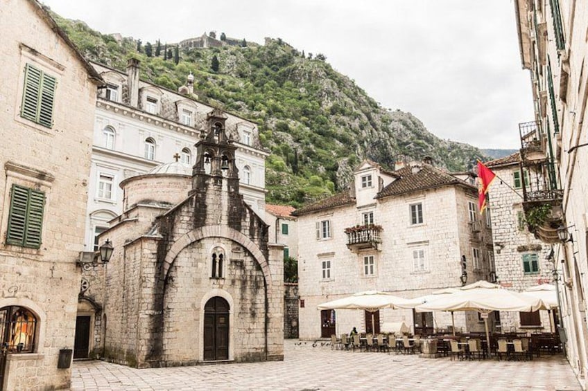 Une église historique dotée d’un clocher, une cour avec des tables et des chaises, et un drapeau flottant sur un bâtiment. 4