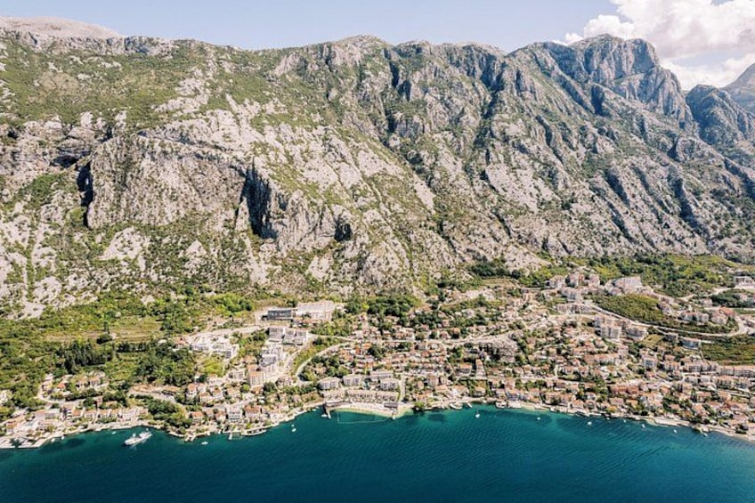 A coastal town nestled between mountains, with buildings along the shoreline and boats in the water. 3