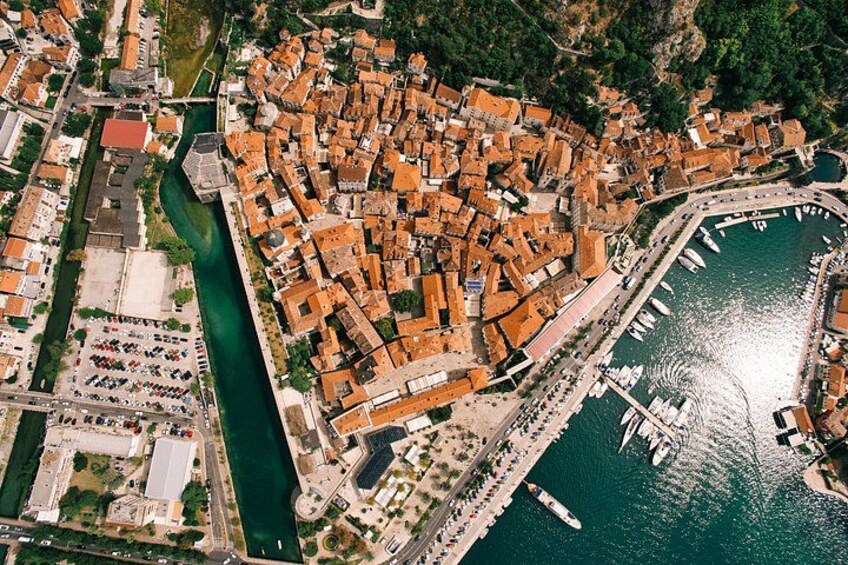 Une vue aérienne d’une ville côtière, avec un ensemble dense de bâtiments, un port de plaisance rempli de bateaux et une rivière qui traverse le centre-ville. 5