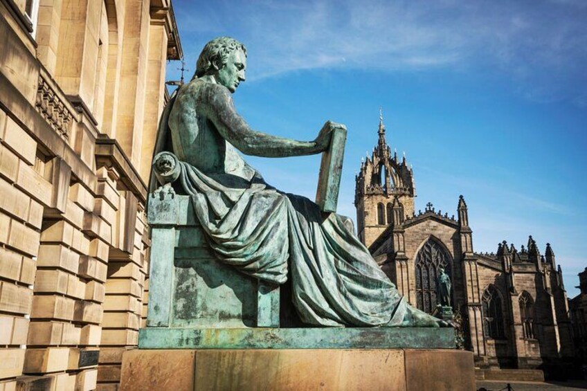 A statue of a seated figure with a building and a church in the background. 2