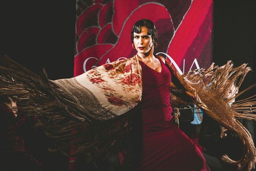 Una persona con un vestido rojo y un adorno de plumas. 1