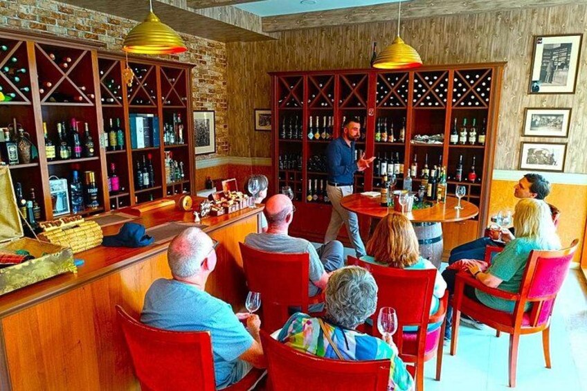 A bar with wooden shelves filled with bottles, a bartender, and seated patrons. 4