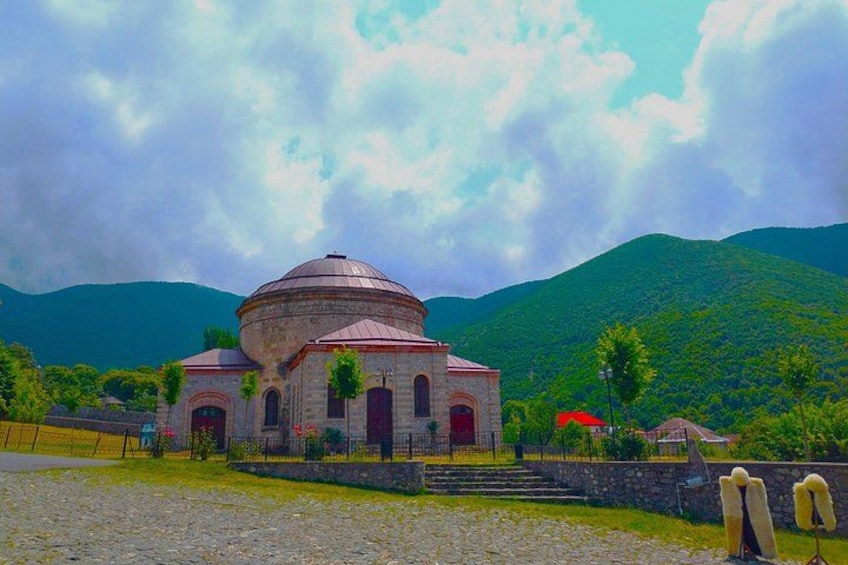 A church with a dome, surrounded by a stone wall, with mountains in the background. 3
