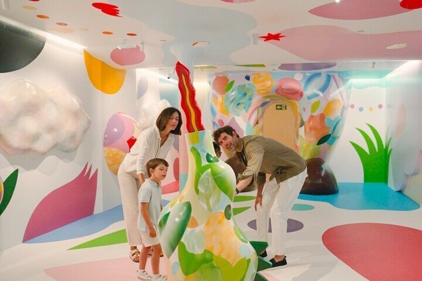 A colorful indoor play area with abstract wall designs and a large inflatable slide. 1