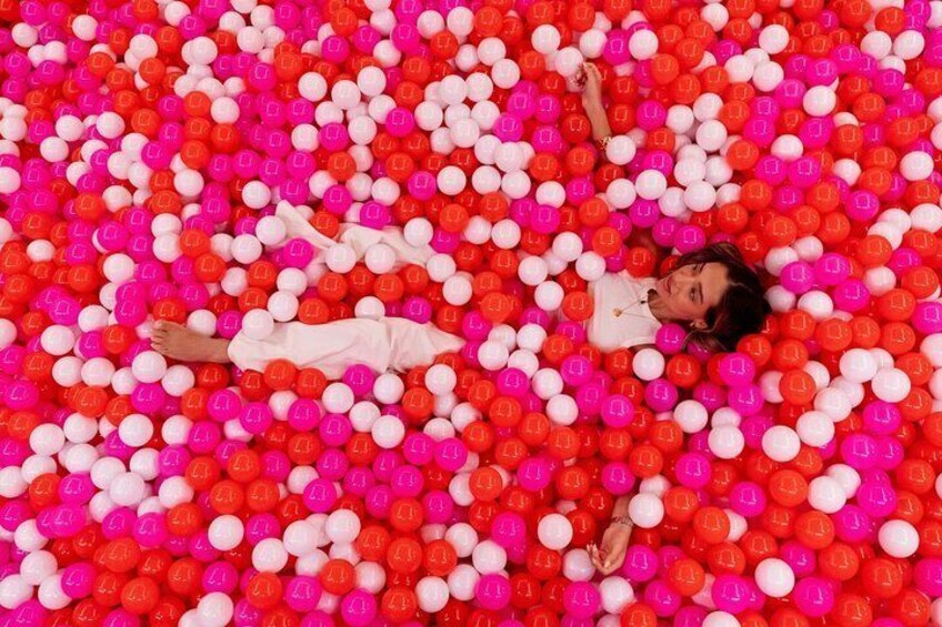 A person lying in a ball pit filled with red and white balls. 4