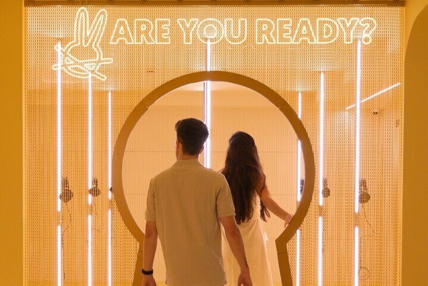 A couple standing in front of a neon sign with the text "ARE YOU READY?" 5