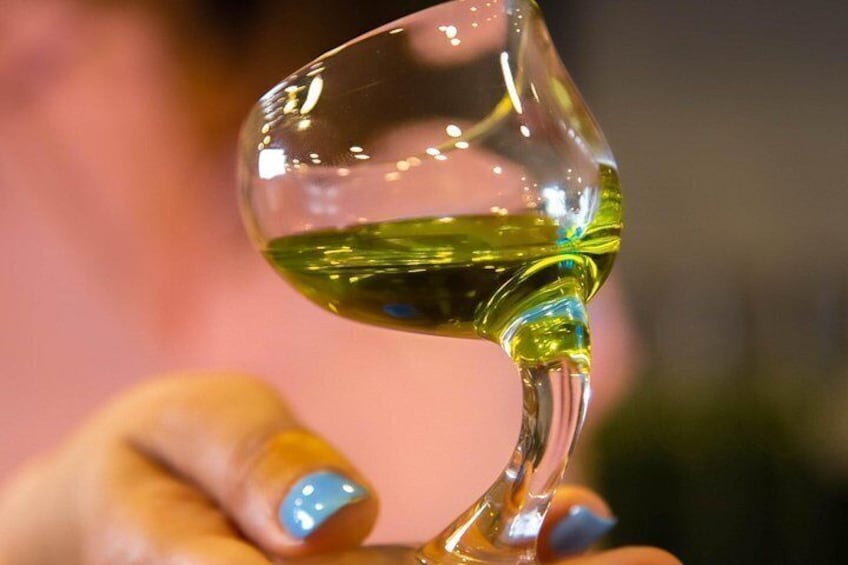 Et klart glas med grøn væske, holdt af en hånd med blå neglelak. 1