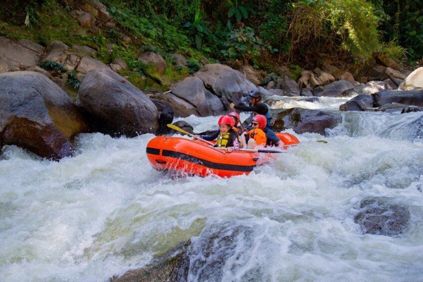 A white-water rafting trip with a group in an orange raft navigating rapids. 4
