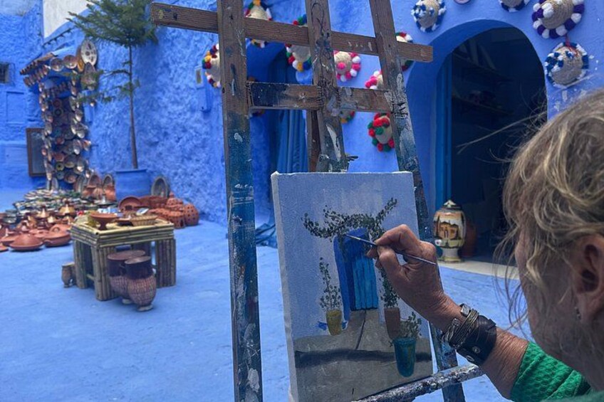 A person painting on a canvas with a blue background. 2