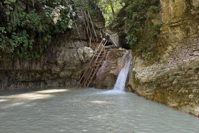 Ein Wasserfall, eine Holzleiter und ein felsiger Klippenhang. 2