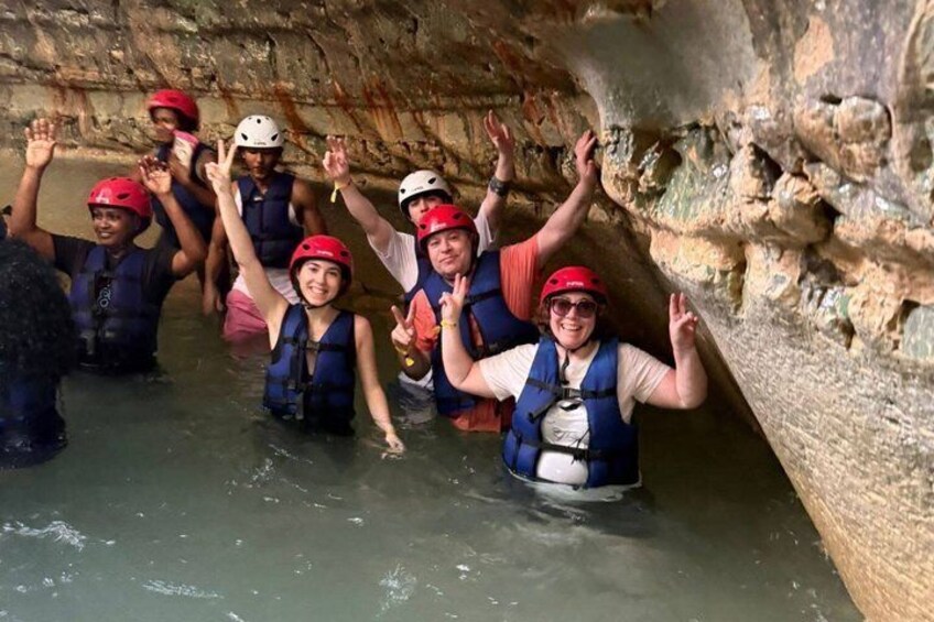 Eine Gruppe von Personen in einer Höhle mit Wasser, ausgestattet mit Helmen und Schwimmwesten. 4