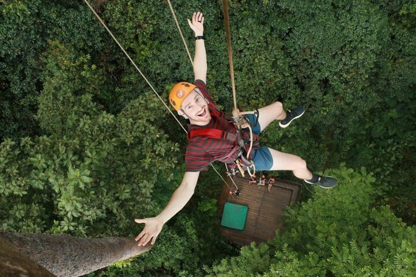 Eine Person schwebt in der Luft, ausgestattet mit Helm und Sicherheitsgurt, verbunden mit einem Seil und einer Plattform. 5