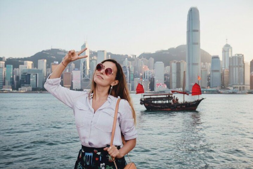 A person taking a selfie with a city skyline and a boat in the background. 2