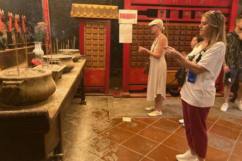 Interieur van een tempel met wierookbrander, een rood altaar en een persoon die toekijkt. 3